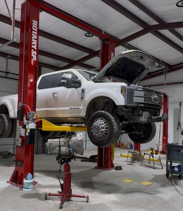 White pickup truck lifted on red automotive lift in professional garage workshop