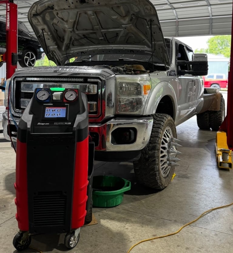 Pickup truck with open hood in auto repair shop with red and black diagnostic machine in foreground