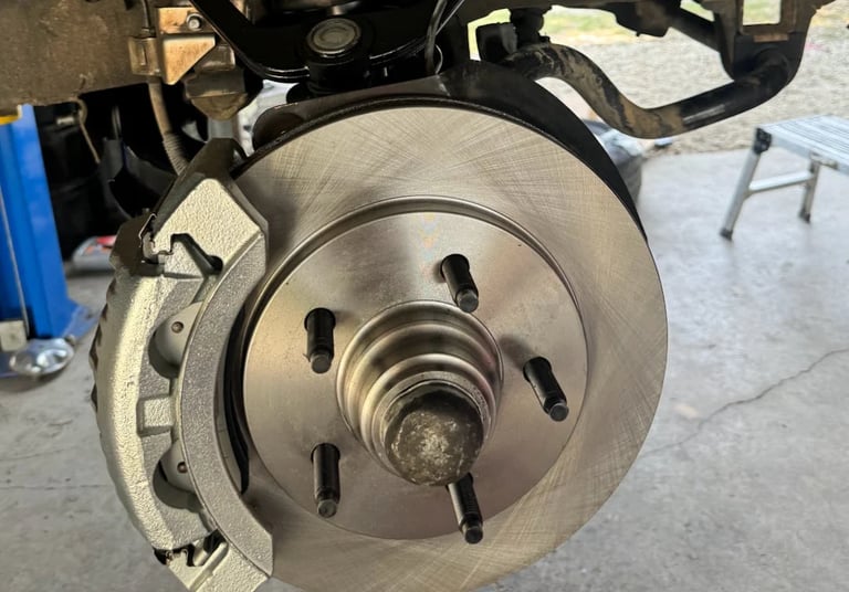 Close-up of a brake rotor and caliper assembly on a vehicle in a garage workshop